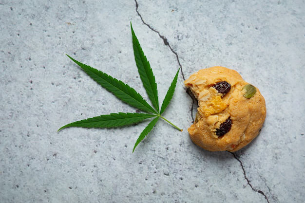 cannabis cookie placed beside a cannabis leaf on a textured surface